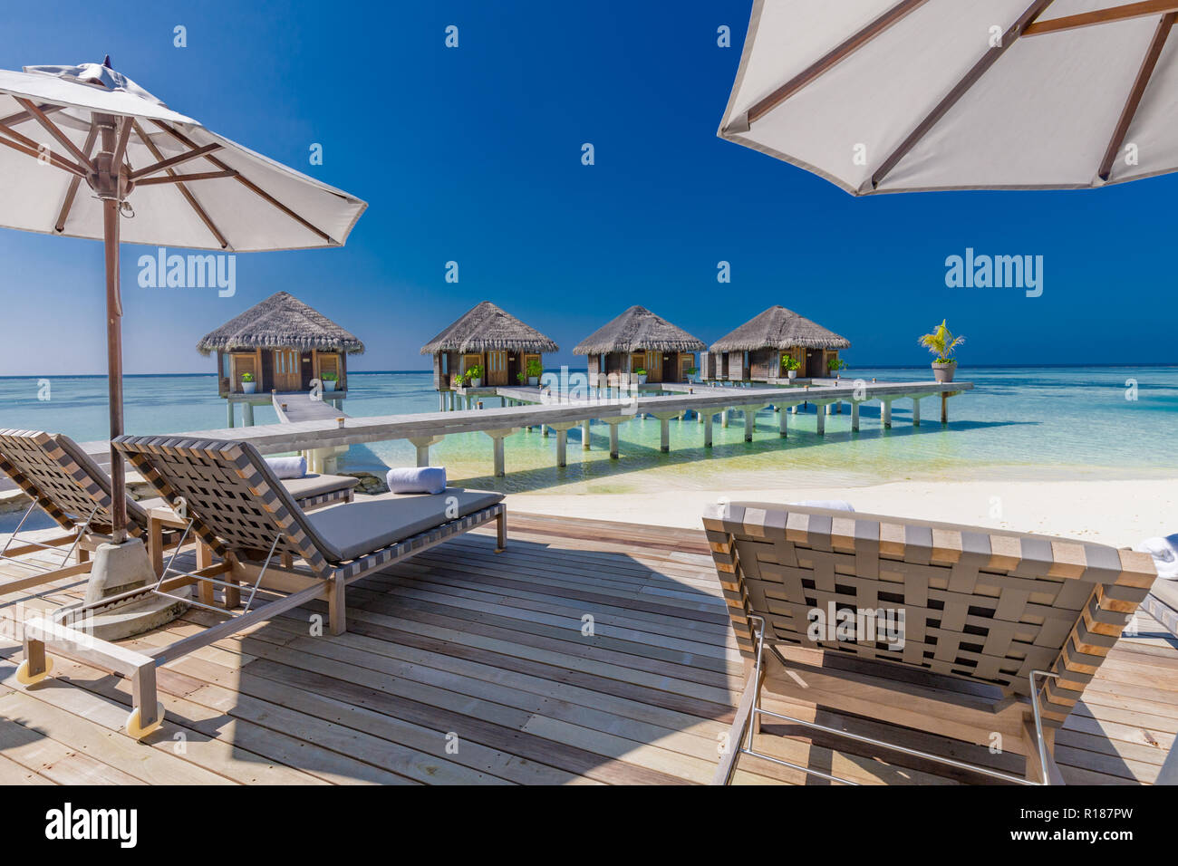 Luxury Beach spa und wellness Hintergrund, Liegen und Liegestühle mit Sonnenschirm auf Holzterrasse. Luxuriöse Resort Spa Hintergrund auf den Malediven. Stockfoto