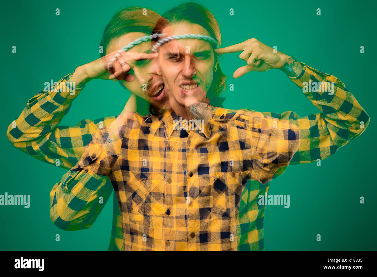 Studio shot von rebellischen jungen Mann gegen grüner Hintergrund Stockfoto