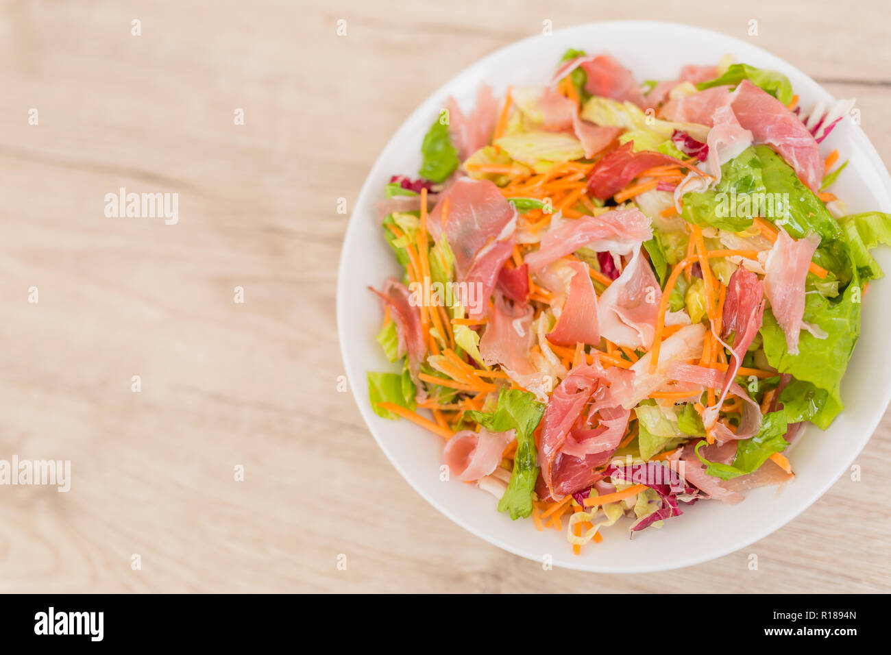 Rucola, Schinken, Mozzarella Salat und Melone auf einem weißen Teller auf einem Holztisch, Ansicht von oben Stockfoto