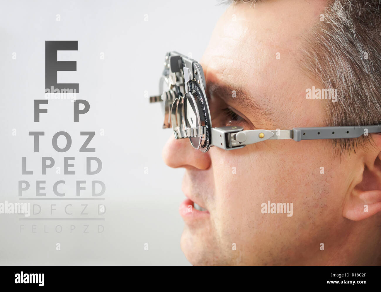 Mann mit Brille Kontrolle Sehvermögen an einer Klinik. Augenarzt Konzept mit Auge Diagramm Stockfoto