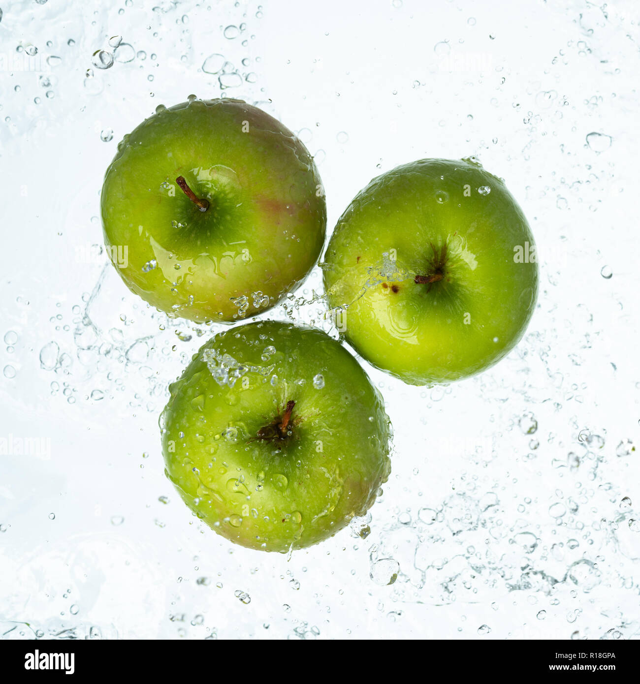 Grüne Äpfel mit Wasser spritzen auf weißem Hintergrund Stockfoto