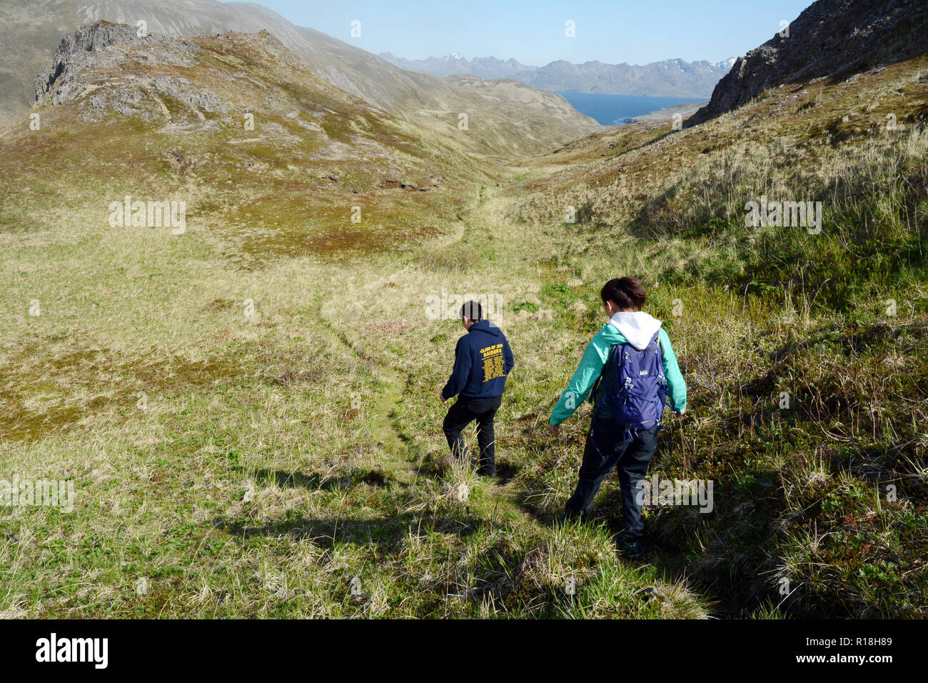 Zwei einheimische Unangan (aleut) Jugend wandern auf einem alten Trail auf den Pazifischen Ozean, in den Aleuten, Unalaska, Alaska, United States. Stockfoto