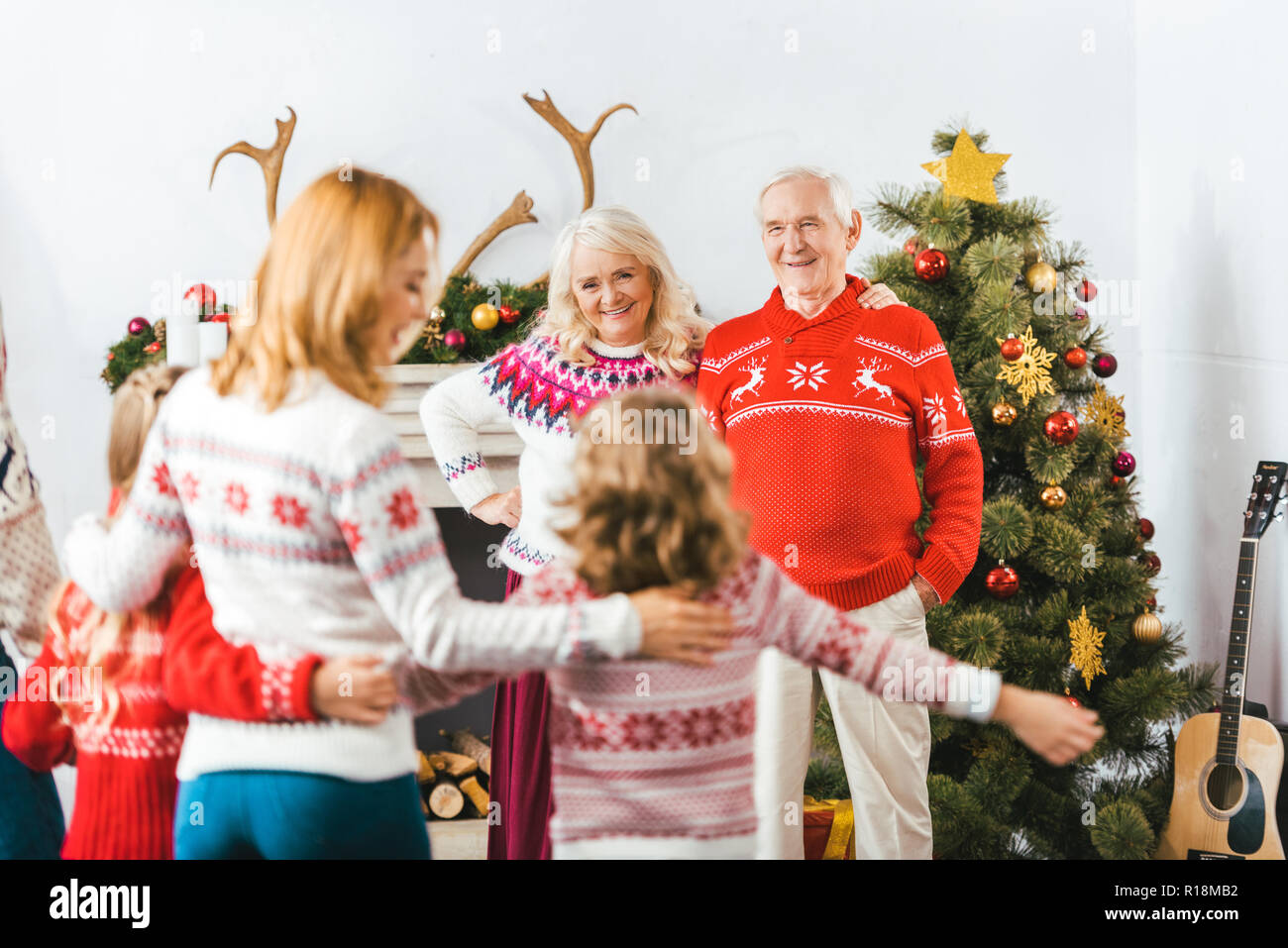 Glückliche Großeltern betrachten Tochter mit den Enkelkindern zu Hause während Weihnachten Stockfoto