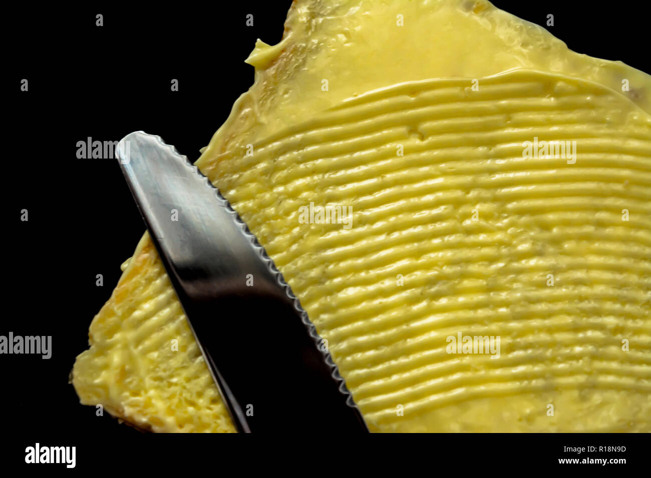 Butter mit schönen Flecken und ein Messer auf einem Stück Brot closeup