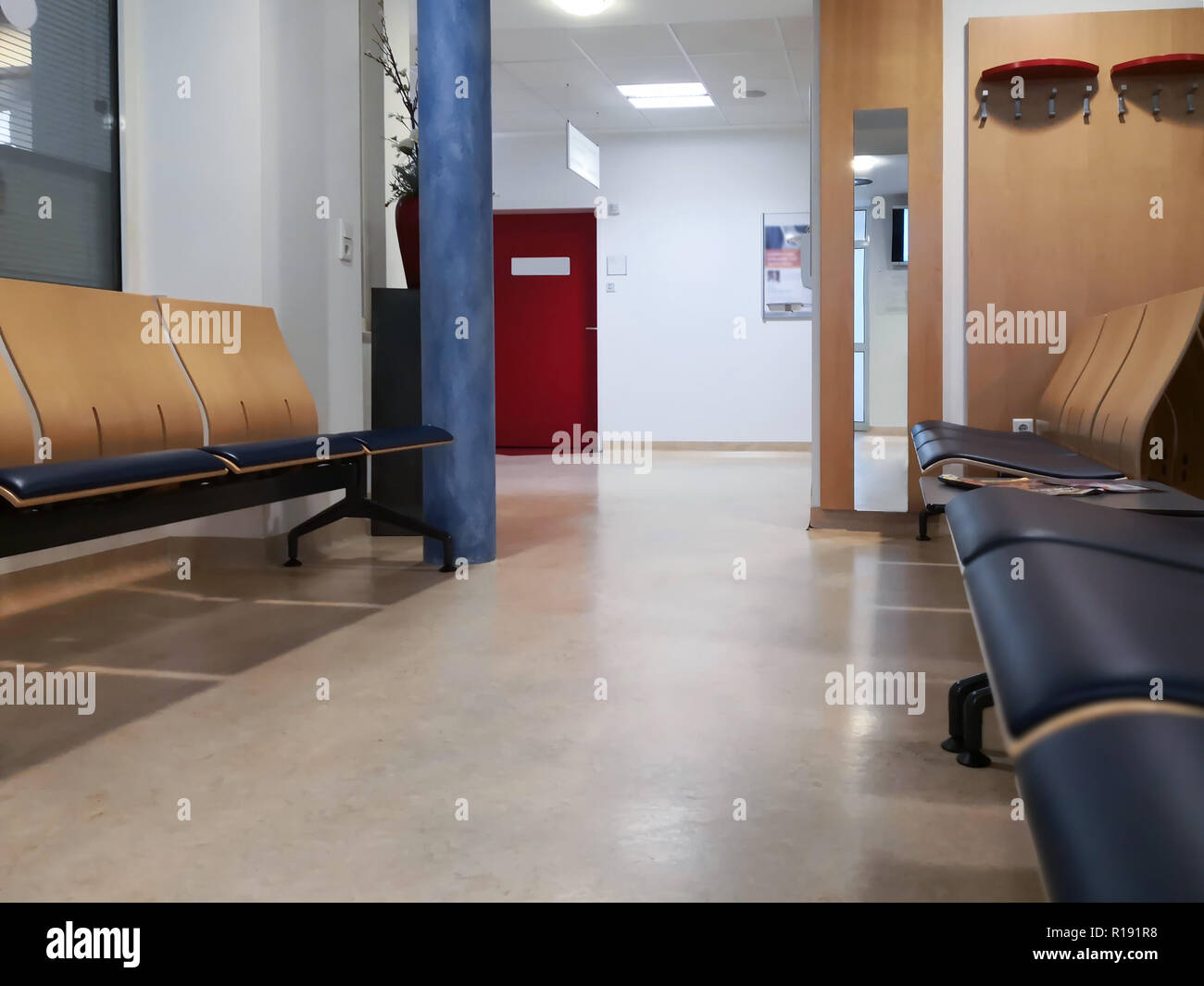 Wartebereich in der Notaufnahme. Eine Sitzgruppe vor einer roten Tür. Die Aufnahme in das Krankenhaus. Stockfoto