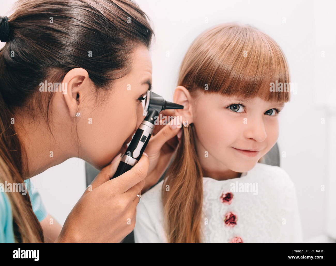 Lächelnd Arzt Prüfung kind Ohr mit Otoskop Stockfoto