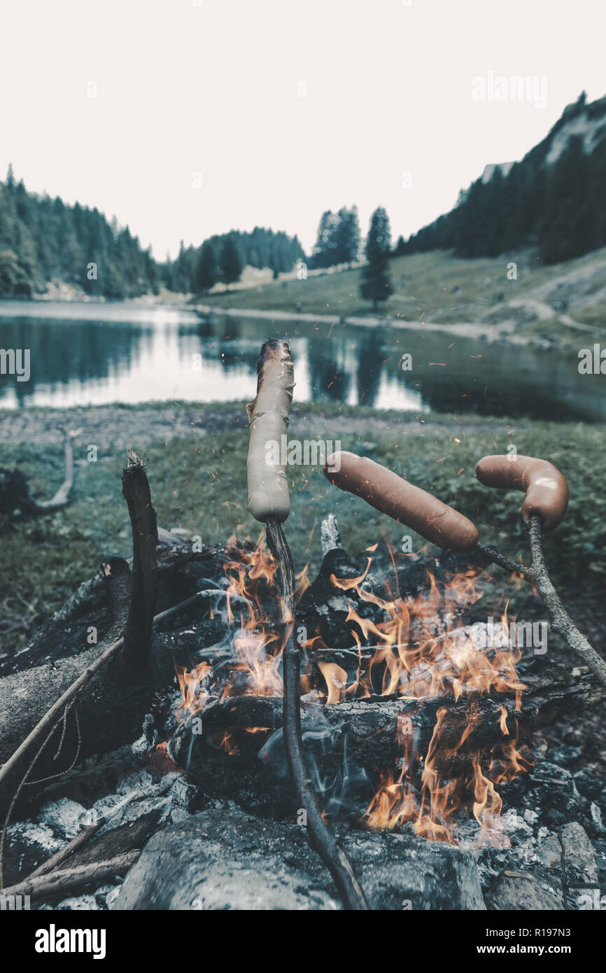 Holzstäbchen Grillen Grill Würstchen auf Kamin in der Bergsee Stockfoto