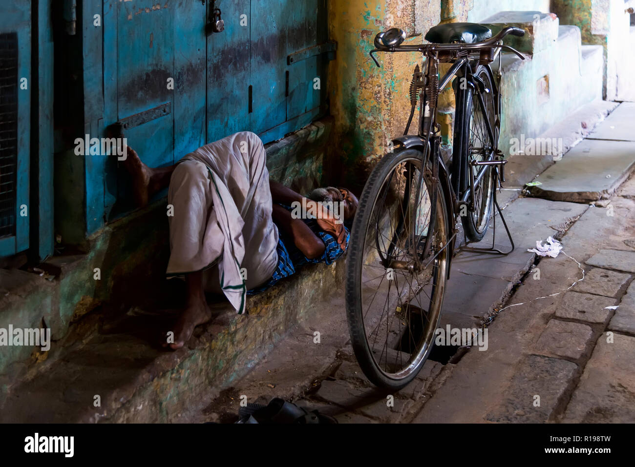 Kumbakonam, Indien - 21. August 2018: alte Mann sitzt vor einem geschlossenen Geschäft in der Kumbakonan Markt Stockfoto