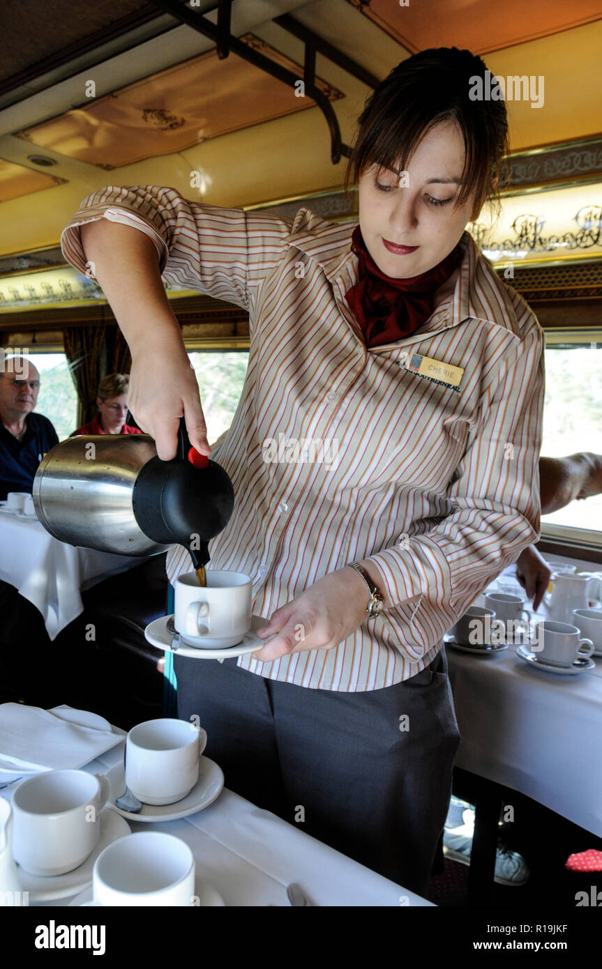 Eine Kellnerin, die Passagieren frischen Kaffee an Bord des erstklassigen Restaurants des Ghan-Zuges in Australien serviert Stockfoto