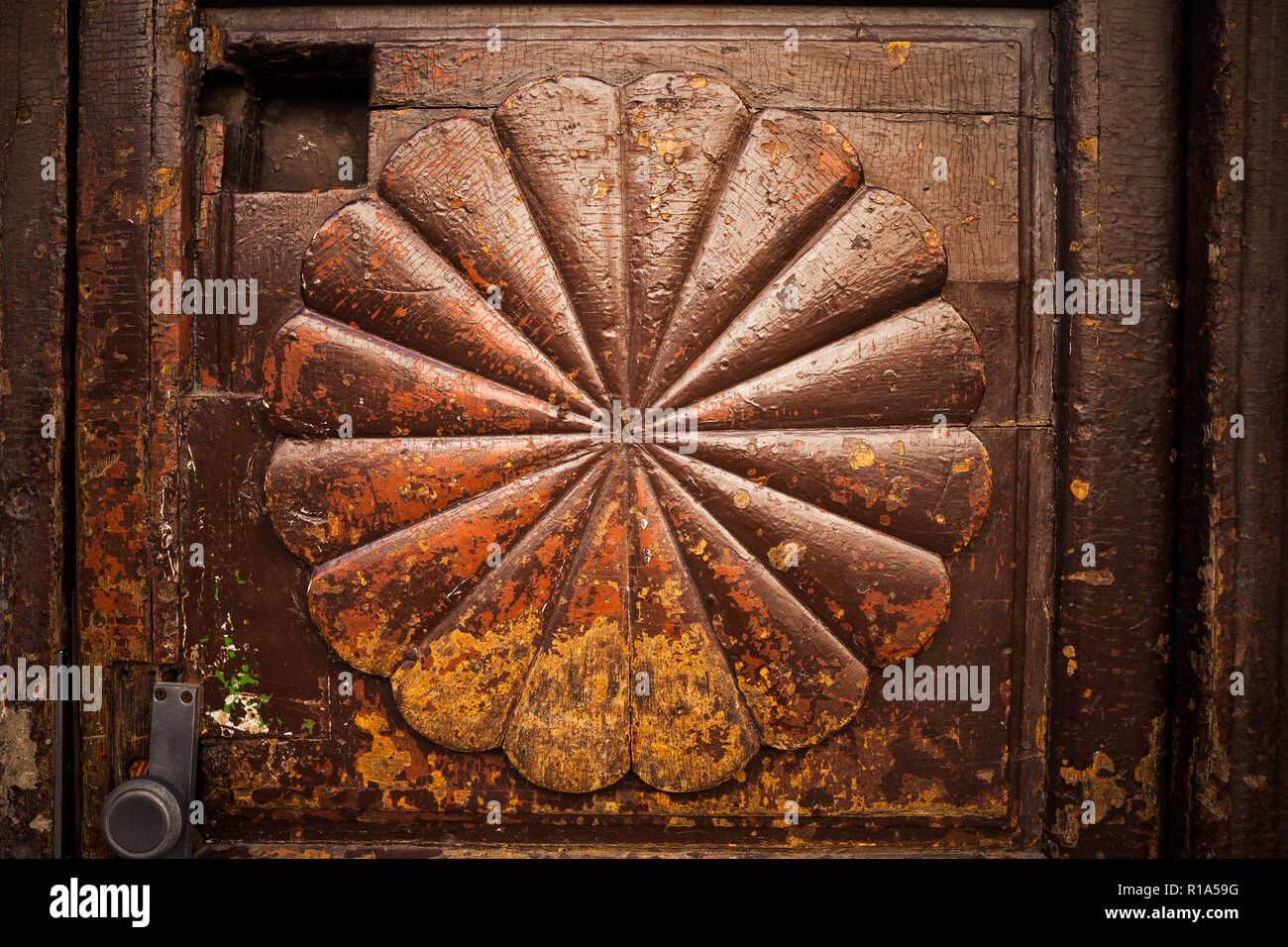 Vintage Holztür mit abstrakten Radiallüfter Form oder Blütenblätter, retro Grunge-look, Peeling und abblätternde Farbe braun mit gelben und orangen Akzenten Stockfoto