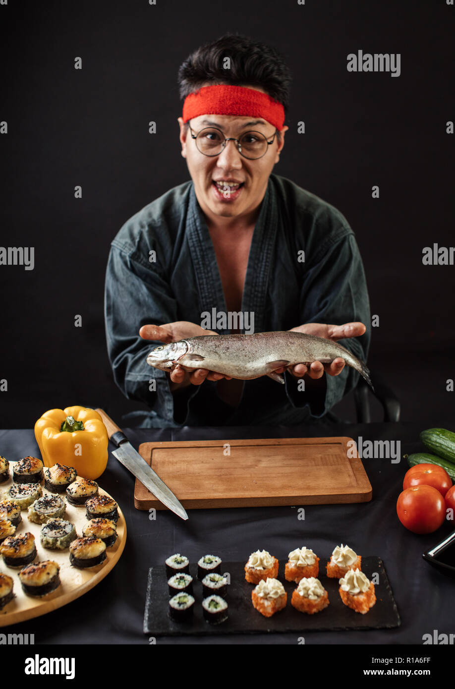 Stattliche assian Chef mit Fisch auf Händen auf der Suche nach einem die Kamera Stockfoto