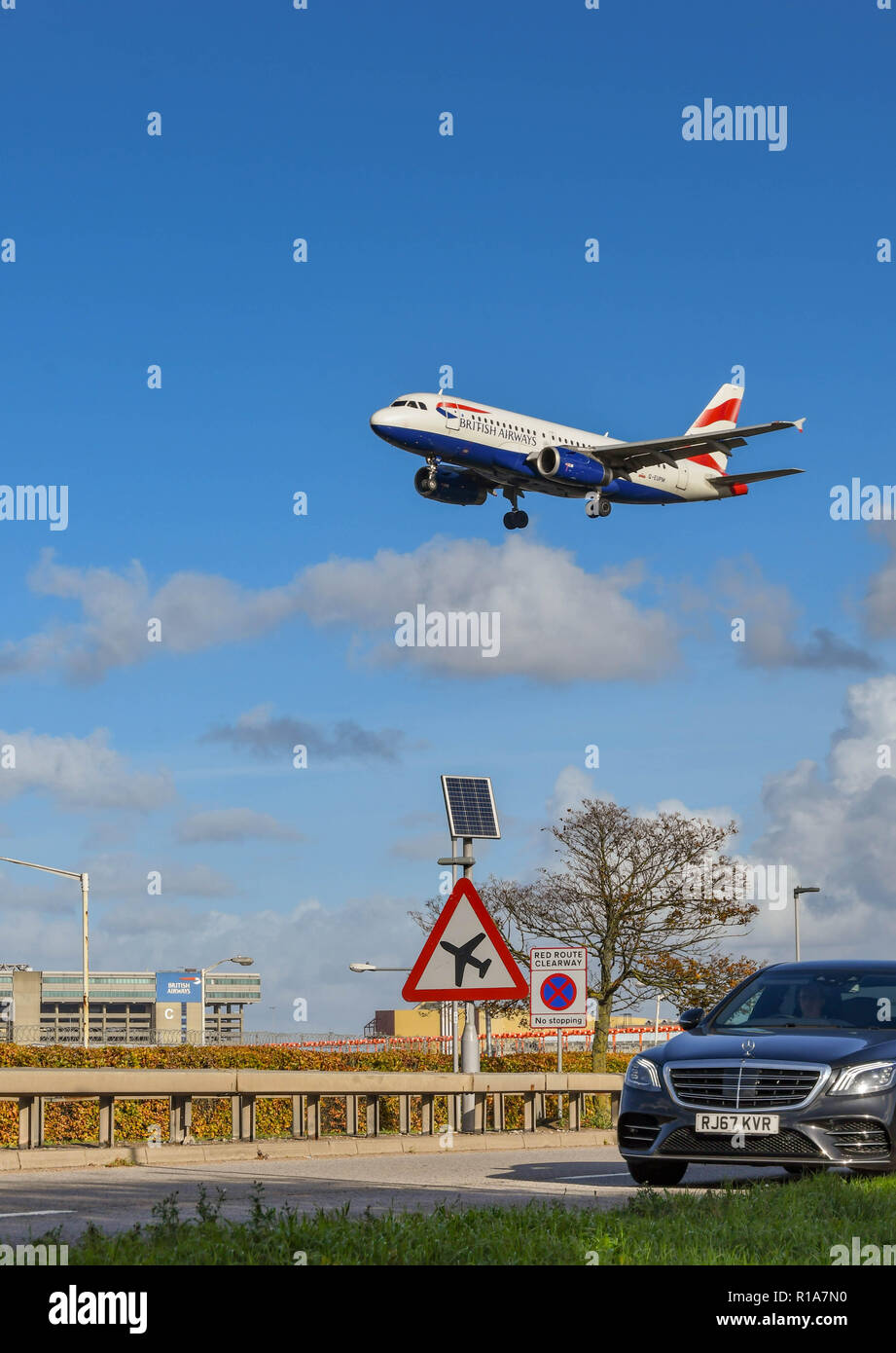 LONDON, ENGLAND - NOVEMBER 2018: Schild auf der 30 Straße am Flughafen London Heathrow Autofahrer rechtzeitig auf tief fliegenden aircarft. Im Hintergrund ist ein Stockfoto