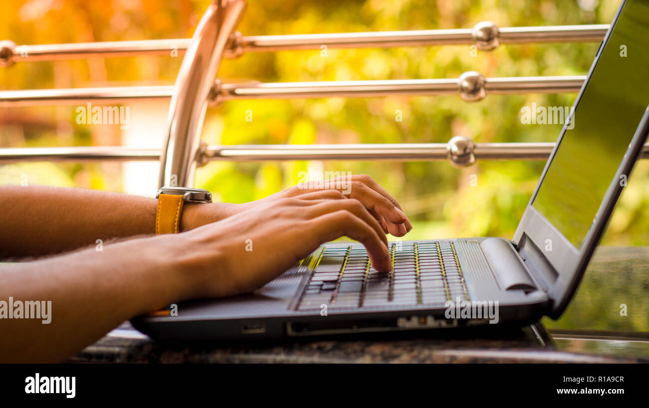 Junge Männer Schreiben auf Laptop Tastatur mit grünem Hintergrund verschwimmen, Stockfoto