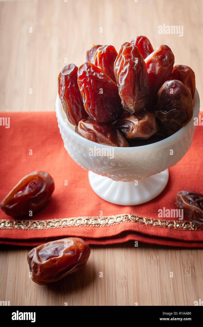 Eine Schüssel mit Organic medjool Termine auf eine gestickte Orange Tuch. Stockfoto