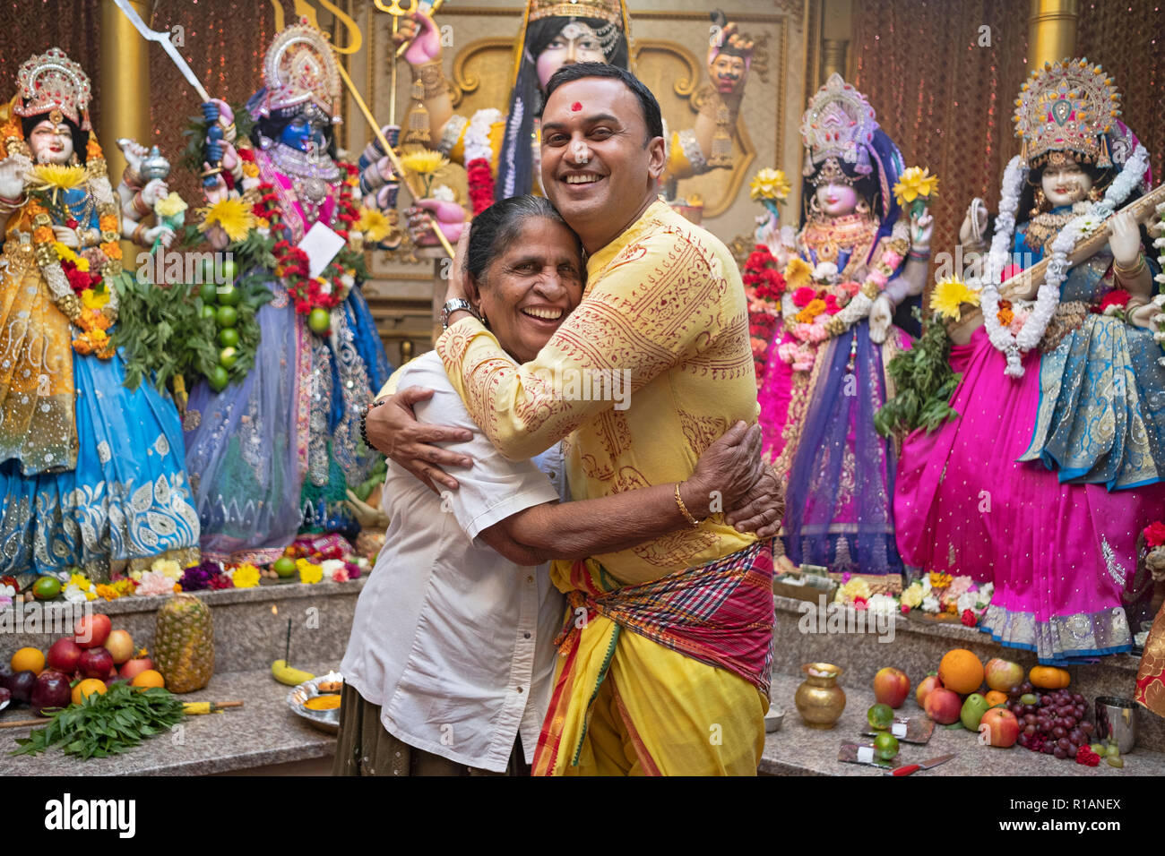 Stellen Portrait von einem frommen Hindu Mann und seine Mutter vor Statuen von Gottheiten an einem Tempel in Ozone Park, Queens, New York. Stockfoto