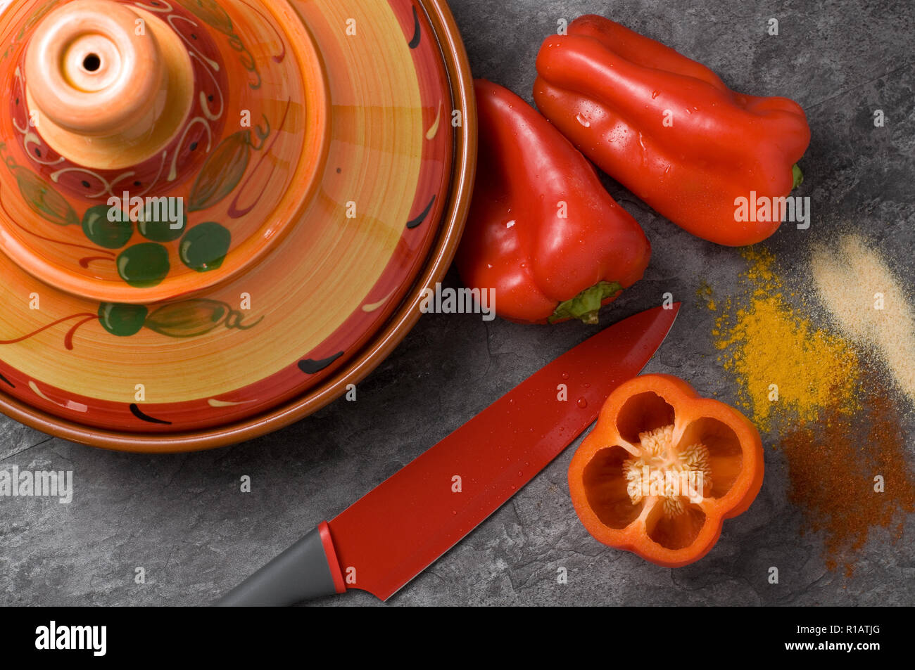 Bunte rote Kochmesser mit frischem Paprika, Gewürze, Tajine auf Granit Zähler Stockfoto