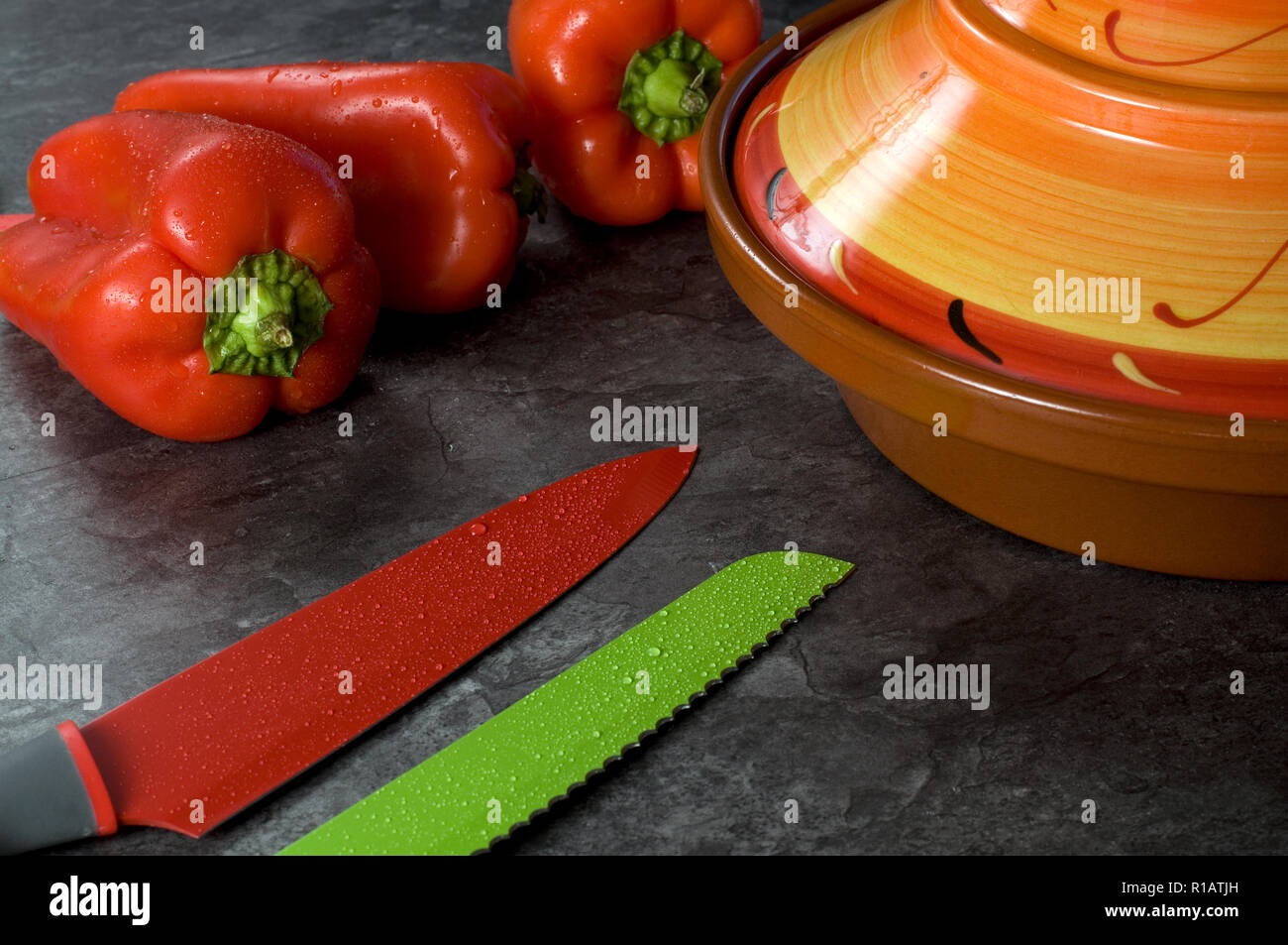 Bunte Reihe von Kochen Messer mit frischem Paprika und Tajine auf Granit Zähler Stockfoto