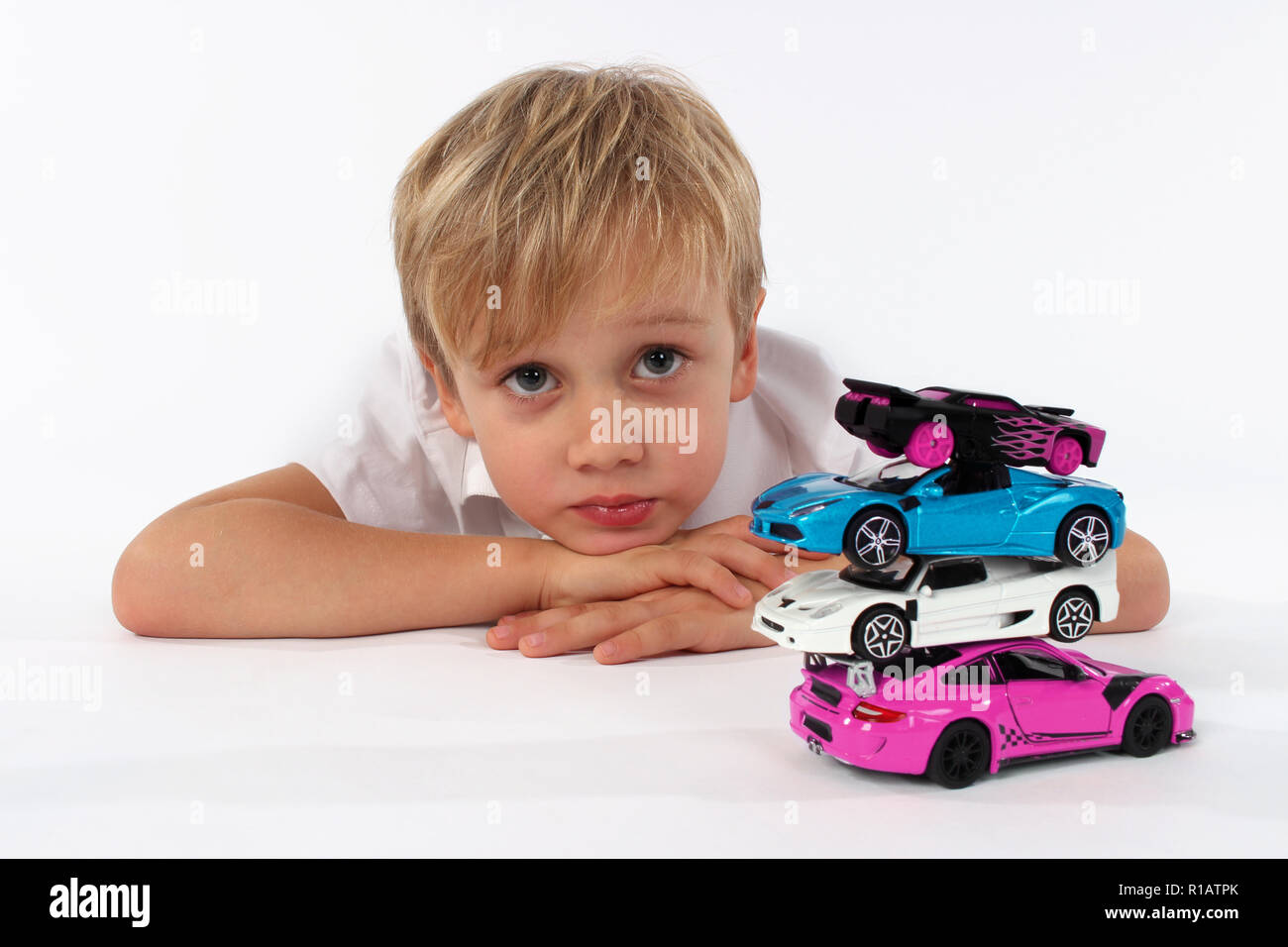 Kind Junge spielt mit Spielzeugautos in einem Studio, bauen einen Turm Stockfoto