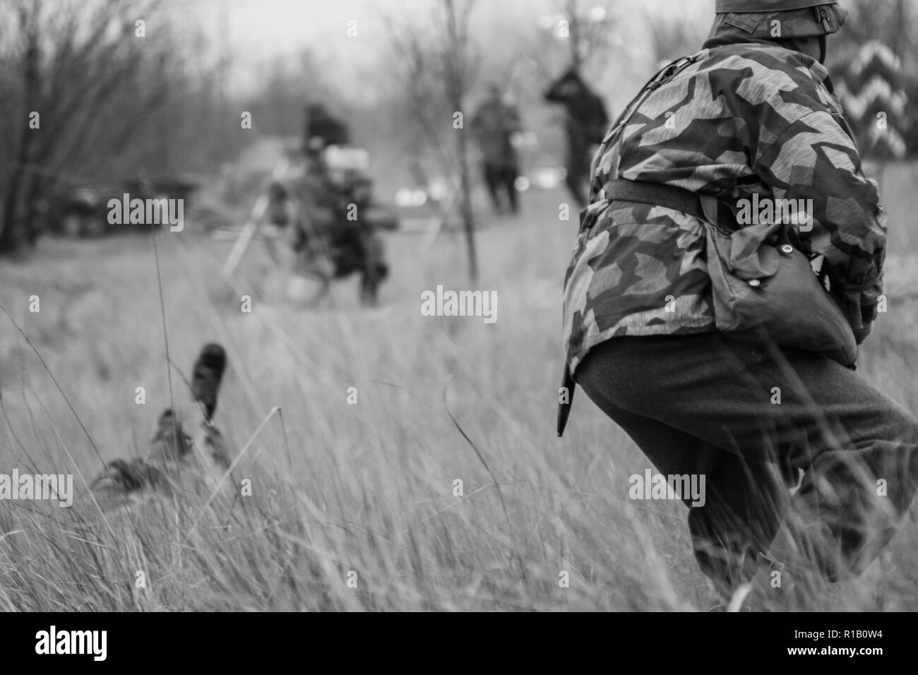 Soldat der Wehrmacht in der Tarnung von hinten im hohen Gras geht zum letzten Angriff Stockfoto