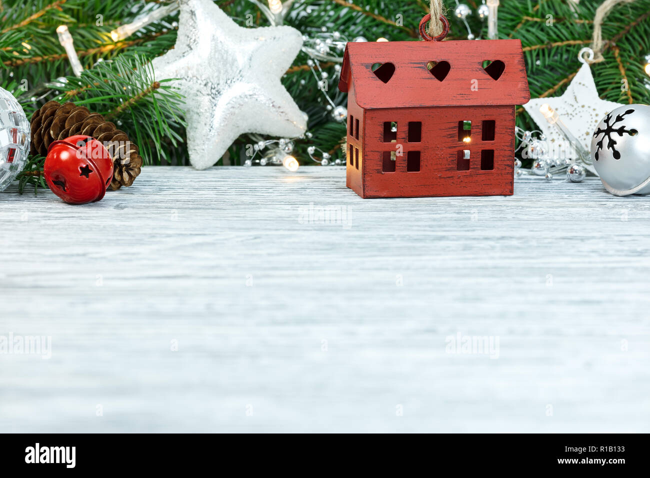 Holztisch mit Weihnachten Fir Tree Branch, Glas, Sterne, Lichter und Jingle bells eingerichtet Stockfoto