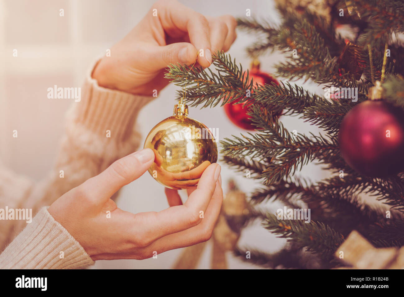 Weibliche Hände hängen Weihnachten Kugel auf Tanne Stockfoto