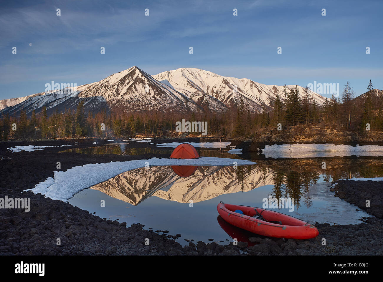 Campingplatz mit orange Zelt und Kanu auf einem See Stockfoto