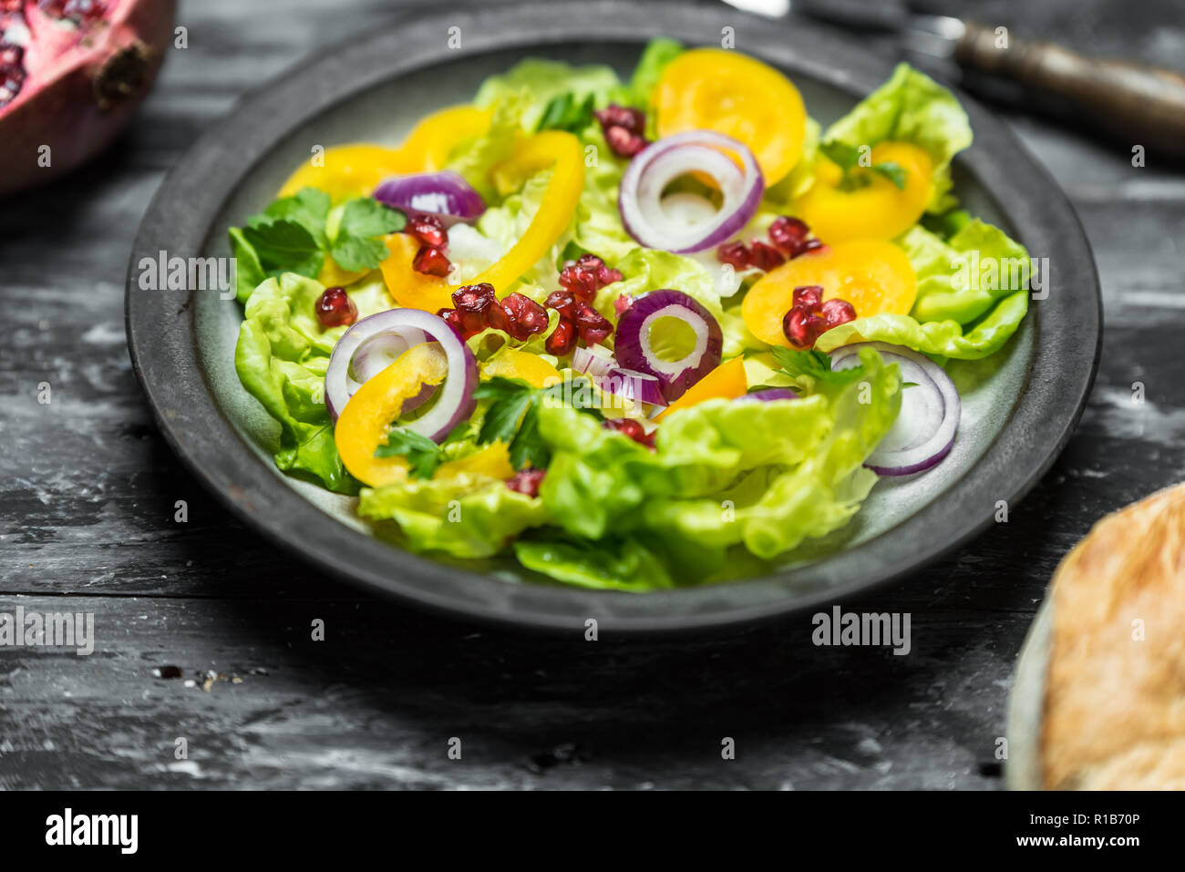 Gesunde Ernährung, frischer Salat mit lila Zwiebel und Granatapfel Samen auf dunklem Holz Hintergrund Stockfoto