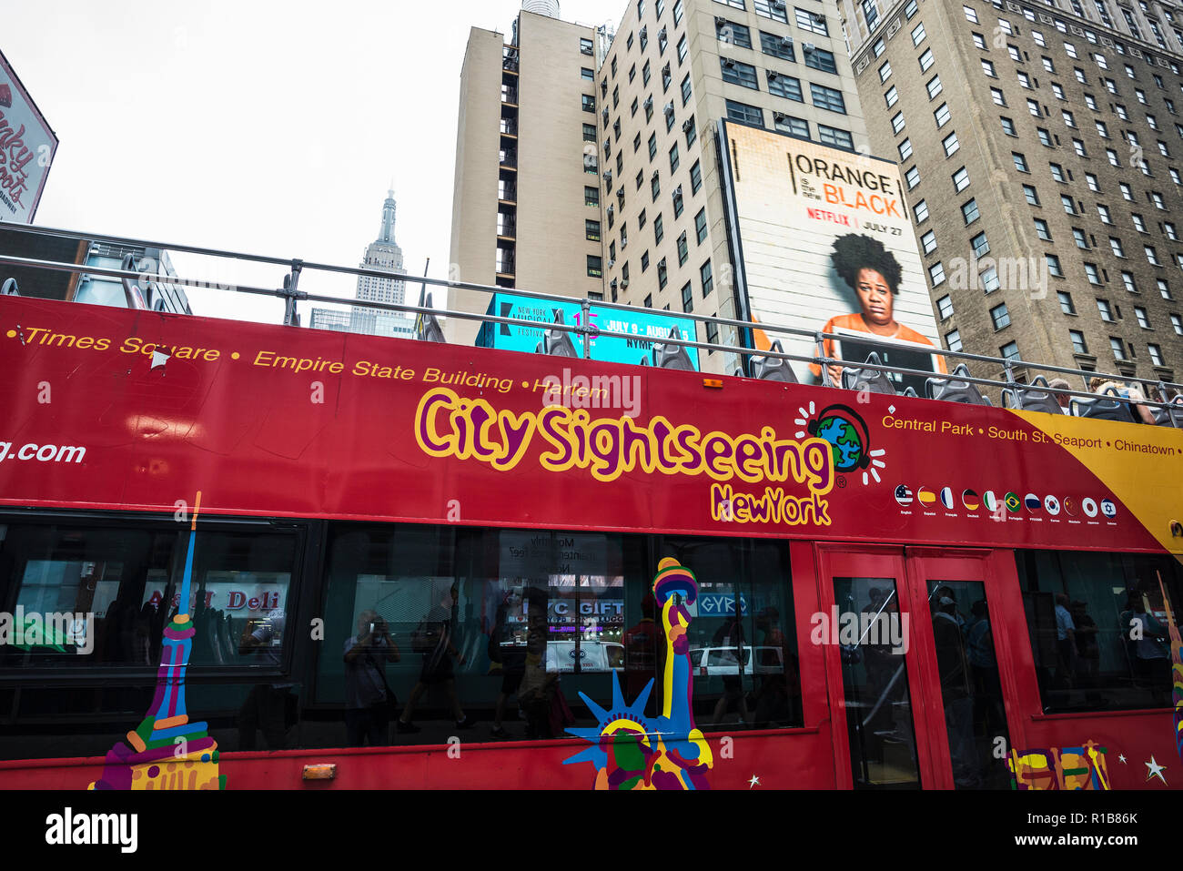 New York City, USA - 25. Juli 2018: Tour Bus auf der Seventh Avenue mit Empire State Building in den Hintergrund und die Menschen in Manhattan in N geparkt Stockfoto