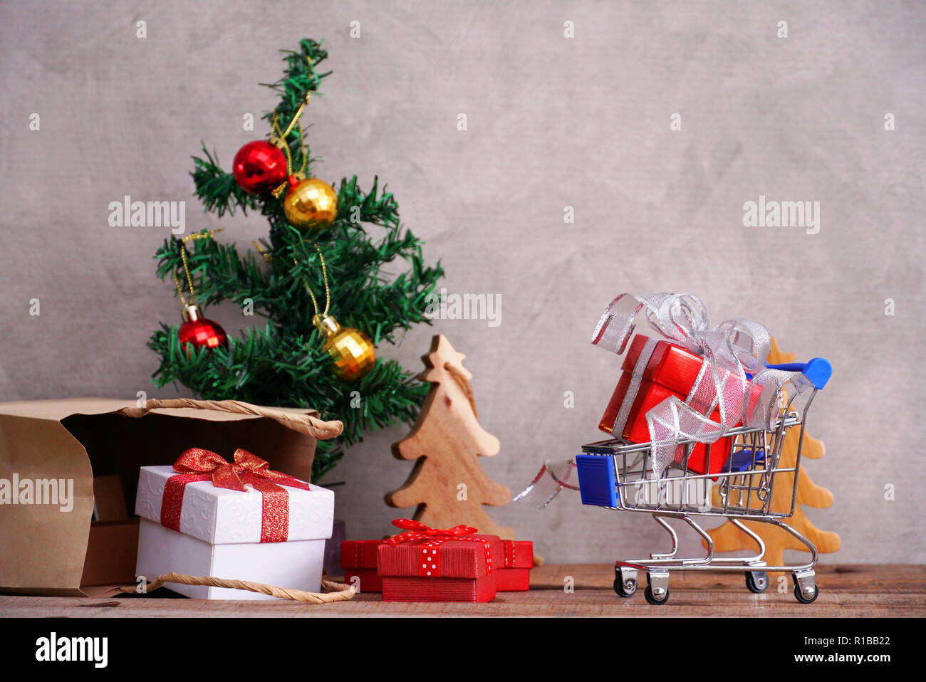 Roter Geschenkbox auf kleinen Wagen mit Hintergrund Geschenkboxen spill aus Papier, Beutel und christmad Baum für Shopping Konzept. Stockfoto