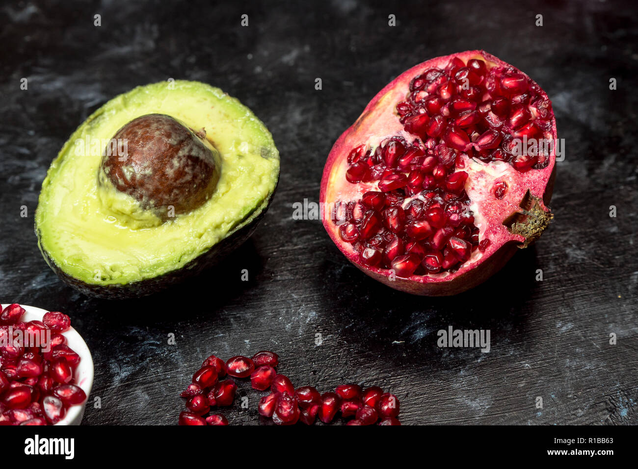 Natürliche Antioxidantien, Avocado Obst bestreut mit Granatapfel Samen, neben einem Granatapfel Stockfoto