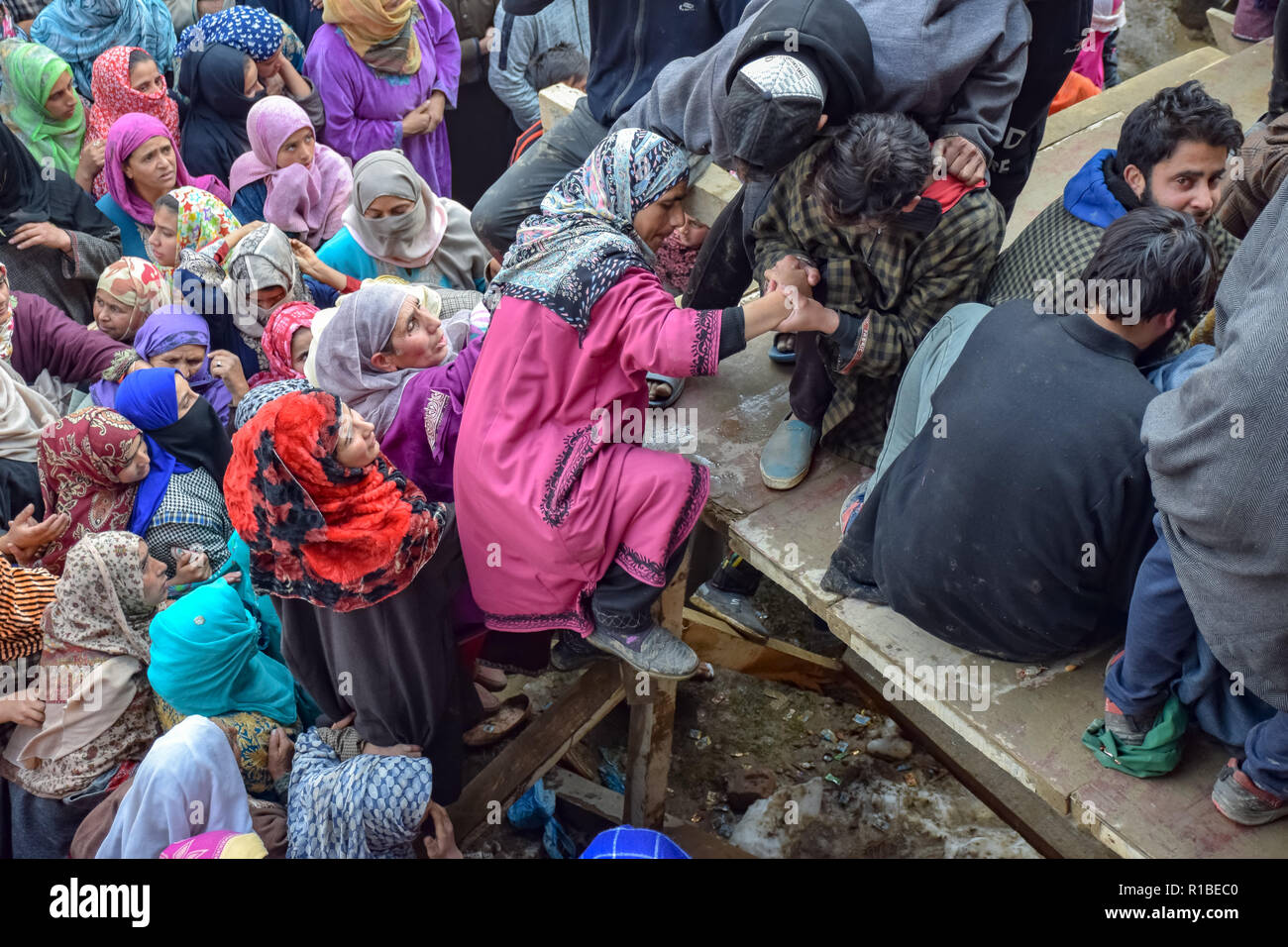 Ein Kaschmirischen Mann gesehen Helfen eines Kaschmirischen Frauen das Gesicht der getöteten Militanten Liyakat Ahmed während seiner Beerdigung Prozession an sein Heimatdorf in Pulwama zu sehen. Tausende von Menschen haben in der Beerdigung Gebete der beiden Kämpfer, der in einer Schießerei mit den Regierungstruppen im Süden von Kaschmir Pulwama Bezirk 40 km vom Sommer Hauptstadt Srinagar getötet wurden, teilgenommen. Die Militanten, entsprechend Generalinspektor der Polizei, Kaschmir, SP Pani, wurden in einer "sehr kurzen "Shootout im Tikken Dorf getötet. Stockfoto