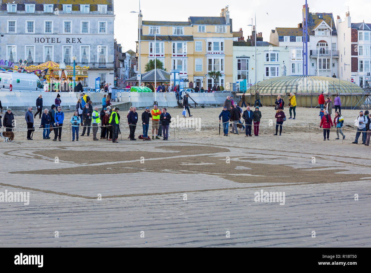 Dorchester, Dorset UK. 11. Nov 2018. Gemeinschaften in Großbritannien sammeln auf Stränden zu 100 Jahre seit dem Waffenstillstand und dem Ende des Ersten Weltkriegs markieren; zu sagen Danke und auf Wiedersehen, die Millionen von Männern und Frauen, die ihre Ufer während des Krieges verlassen, viele nie zurück. Danny Boyle's einzigartigen Seiten des Meeres, wo ein Porträt eines Einzelnen aus dem Ersten WK1 aus dem Sand entsteht und dann, als die Flut steigt, es ist weggespült. Credit: Carolyn Jenkins/Alamy leben Nachrichten Stockfoto