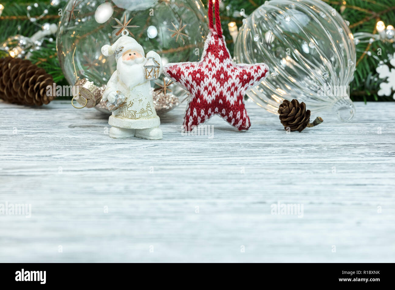 Holztisch mit dekorativen santa Figur, Weihnachtskugeln und Tanne Baum mit Lichtern Girlande Stockfoto