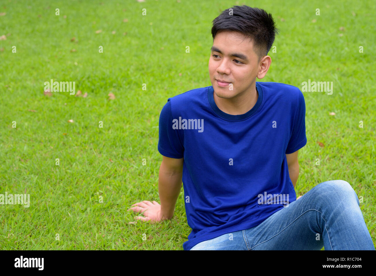 Die Jungen gut aussehenden asiatischer Mann Entspannung im Park Stockfoto