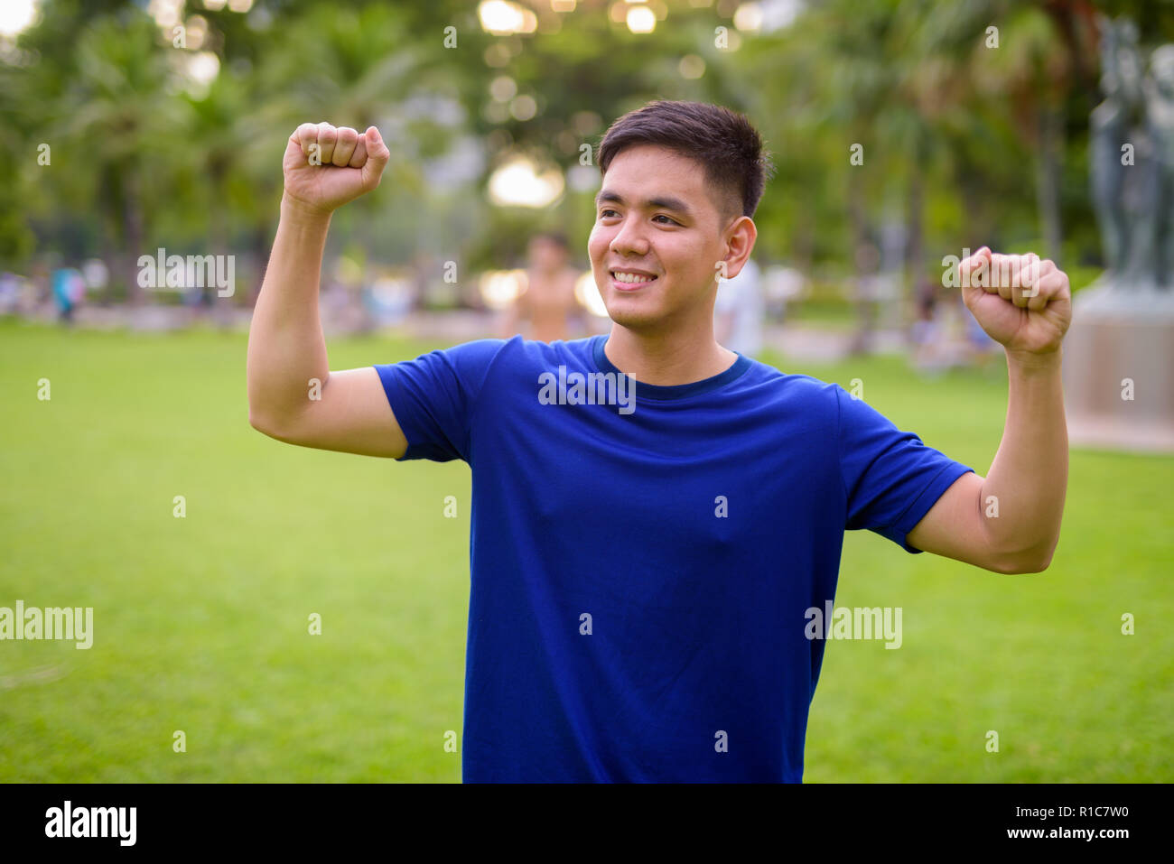 Die Jungen gut aussehenden asiatischer Mann Entspannung im Park mit erhobenen Armen Stockfoto