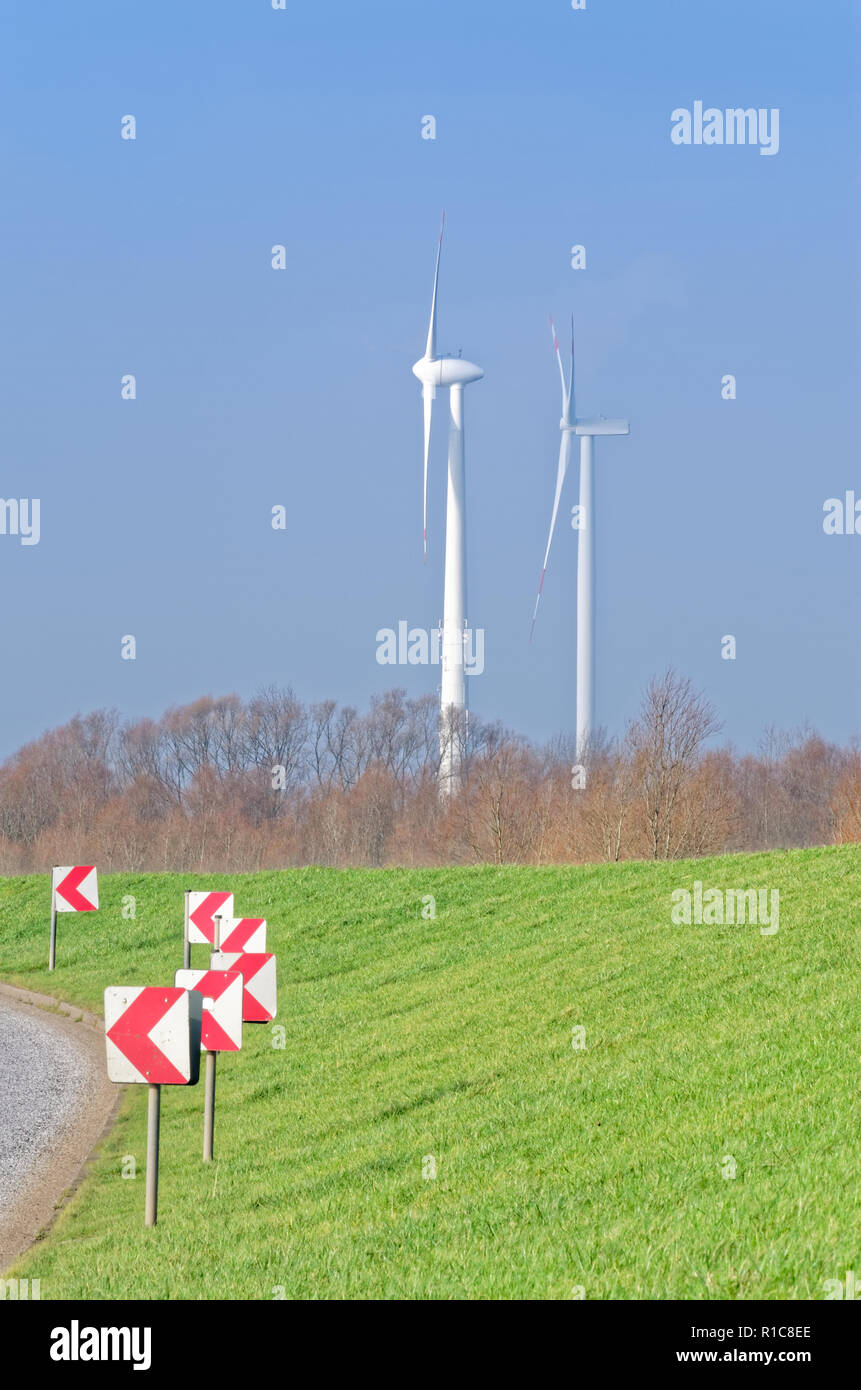 Country Road, grüne Wiese und zwei Windräder auf blauen wolkenlosen Himmel Stockfoto