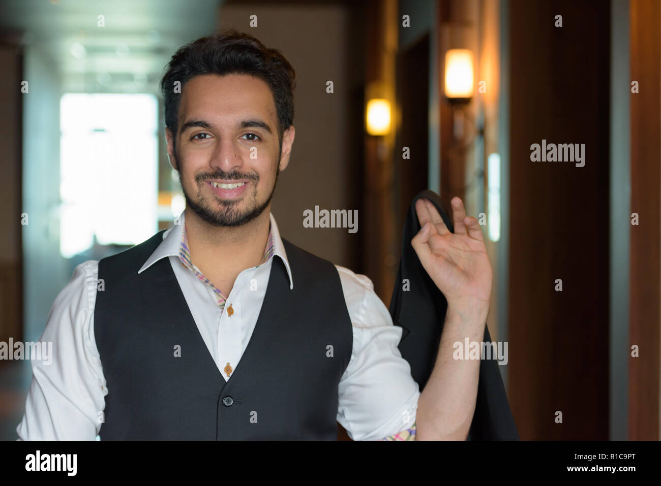Junge glücklich indischen Mann lächelnd, während sie Jacke im corri Stockfoto