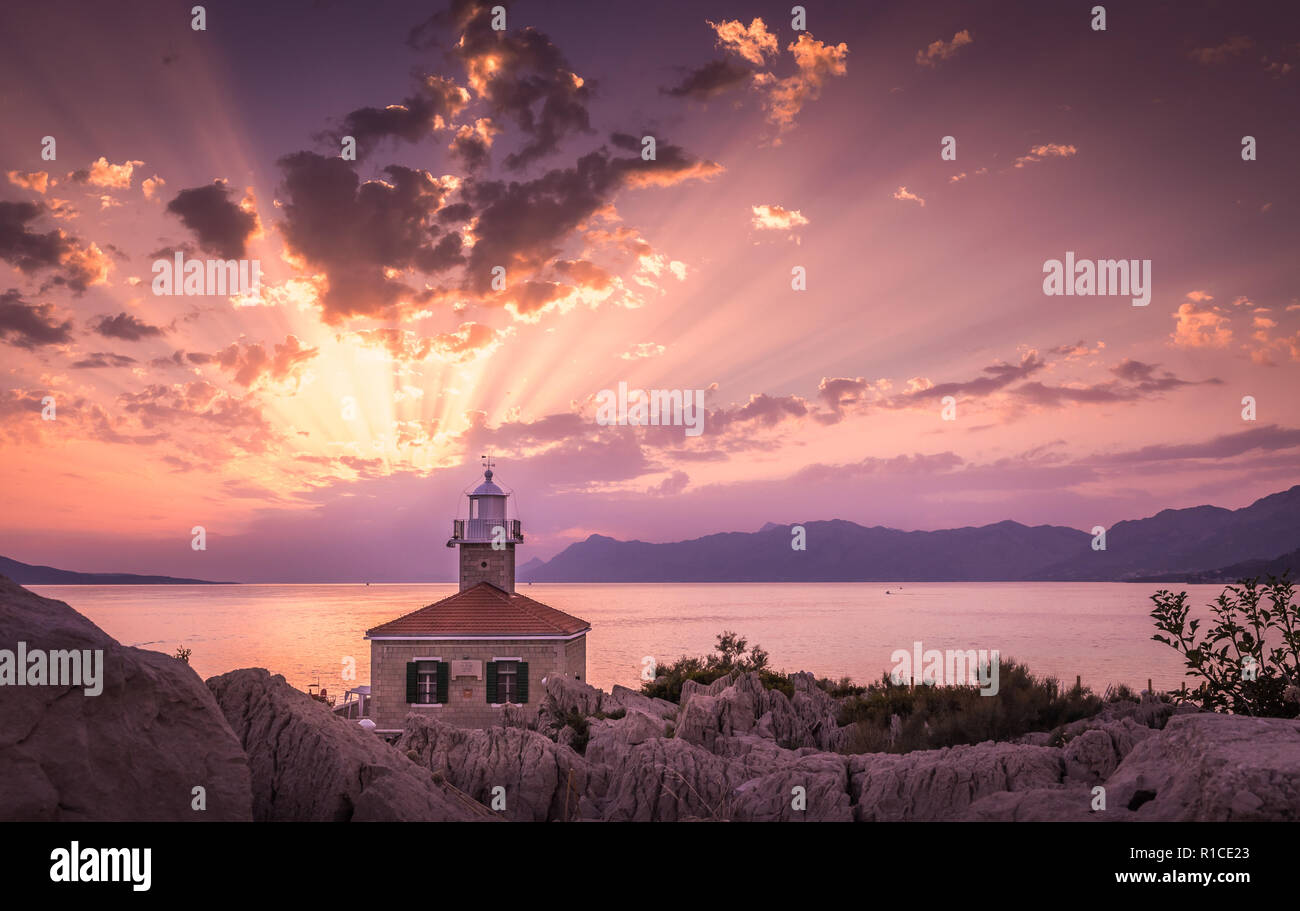 Schönen Sonnenuntergang über dem Mittelmeer mit Leuchtturm im Vordergrund in Makarska, Kroatien Stockfoto