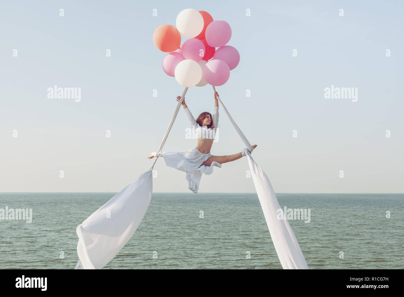 Junge Frau tun Garn auf den Leinwänden über das Meer, sie fliegt auf Luftballons. Stockfoto