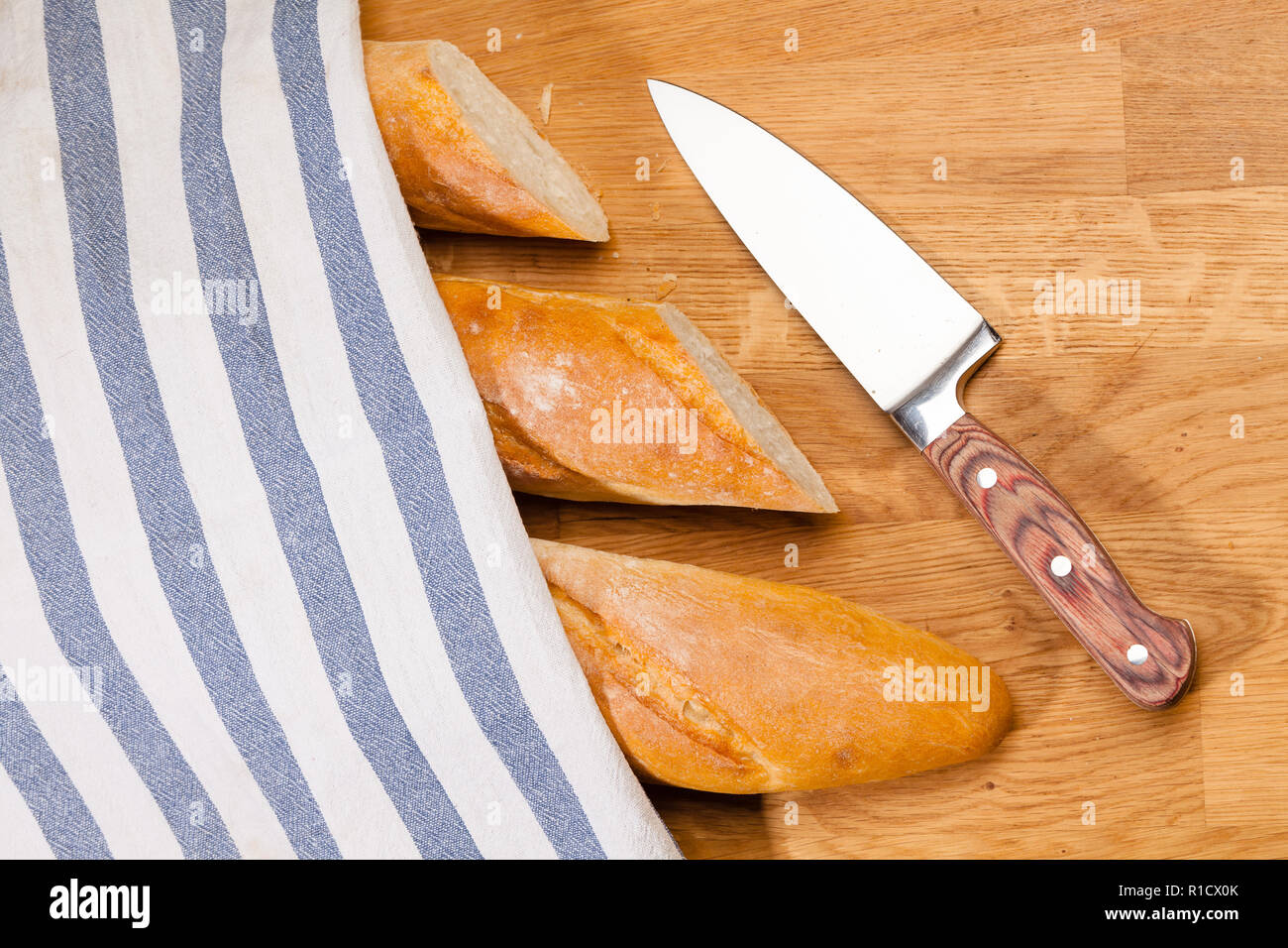 In Scheiben geschnitten sreshly gebackene handwerklichen Baguette (französisches Brot) und Messer auf hölzernen Tisch mit Mehl Stockfoto