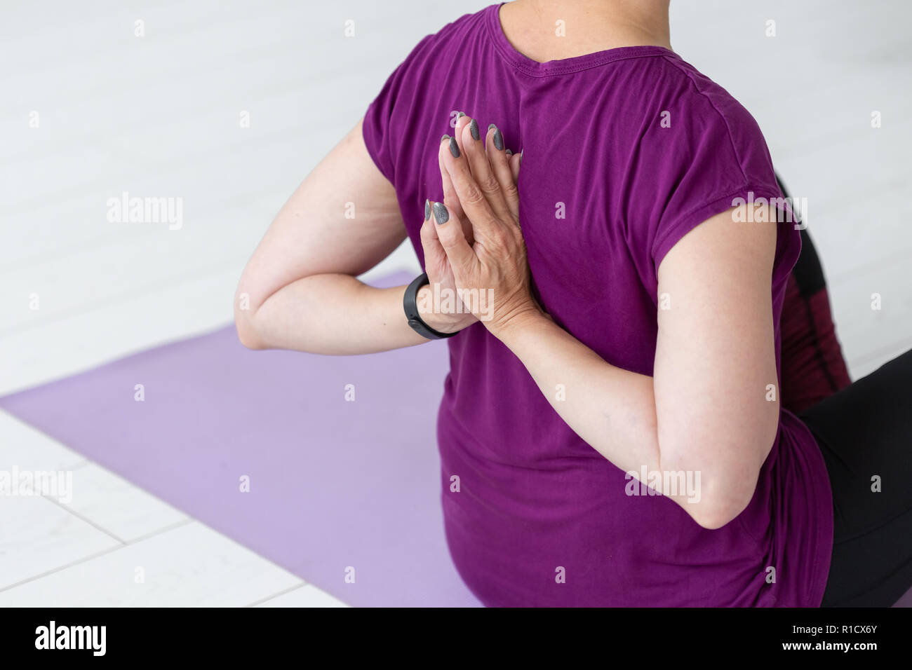 Leute, Sport, Yoga und Gesundheit Konzept - Mitte - gealterte Frau sitzt auf der Yogamatte mit Hände hinter dem Rücken Stockfoto