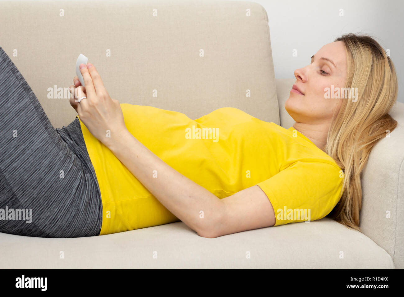 Schwangere Frau auf dem Sofa liegend Stockfoto