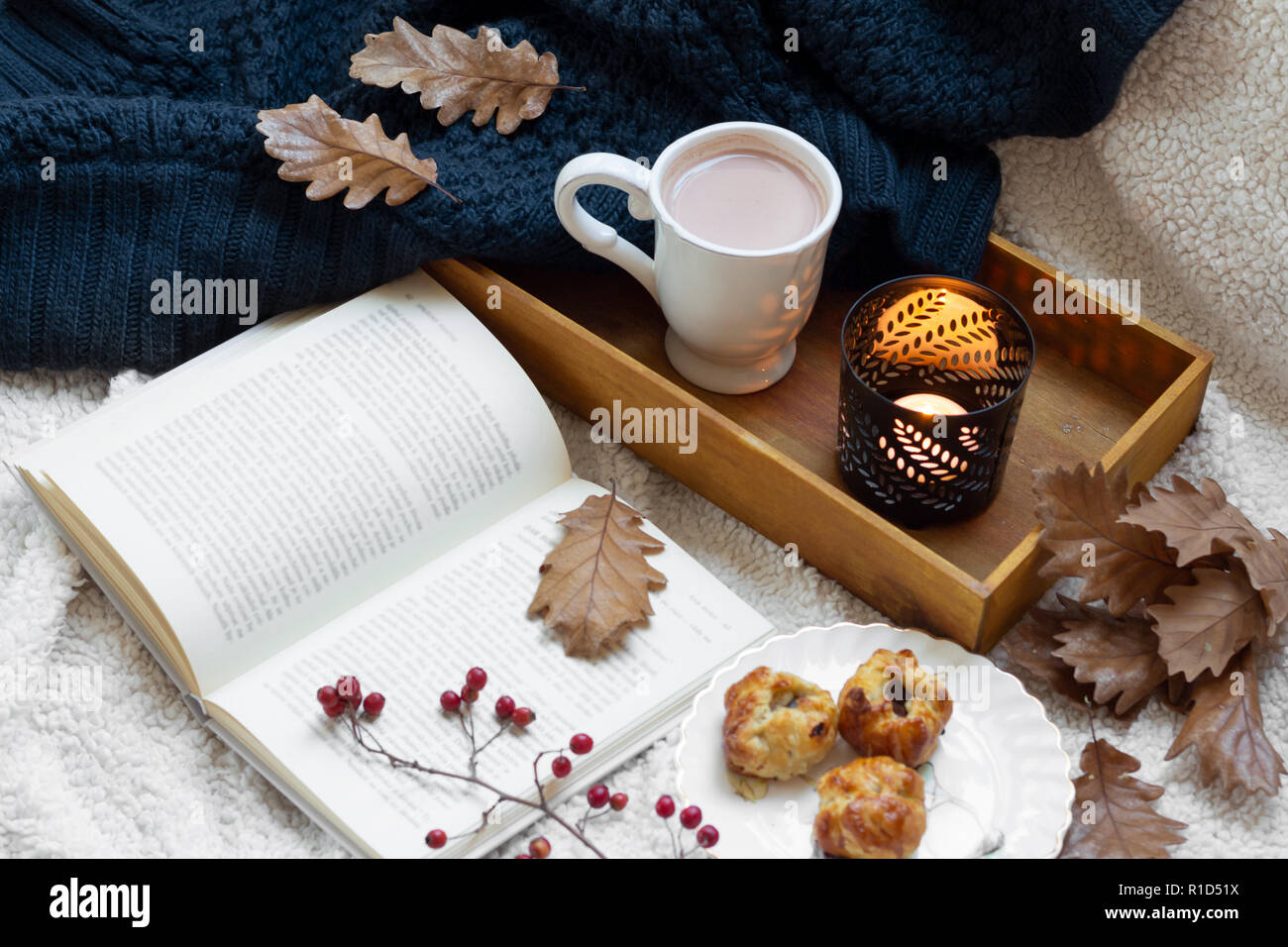 Hygge Stil. Buch und Becher Kaffee in warmen Schal gewickelt. Stockfoto