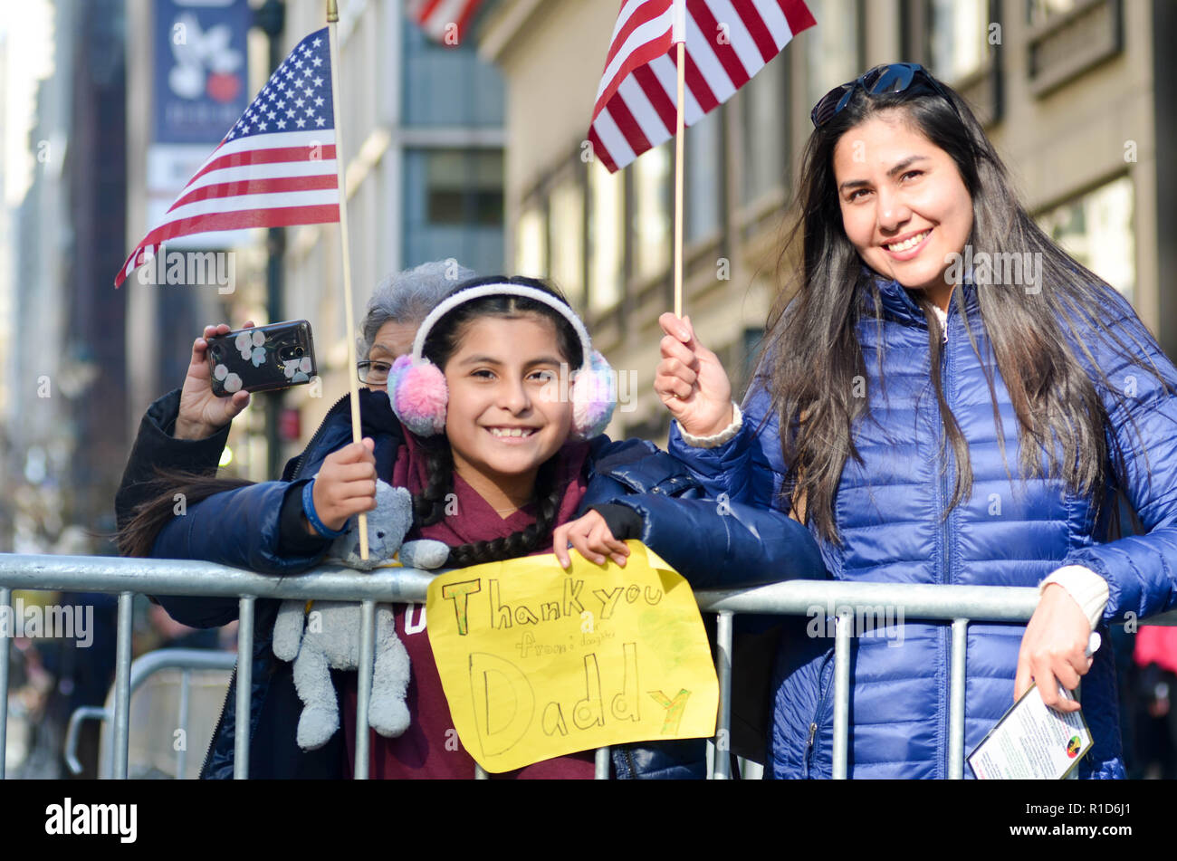 Eine Frau und ein Kind gesehen, die amerikanische Flaggen während der Parade. Tausende von mehr als 300 Einheiten in den Streitkräften nahmen an der jährlichen Veterans Day Parade. Die Veterans Day Parade statt entlang der 5th Avenue in New York City ehrt den Dienst derer, die in den amerikanischen Streitkräften gedient habe. Stockfoto