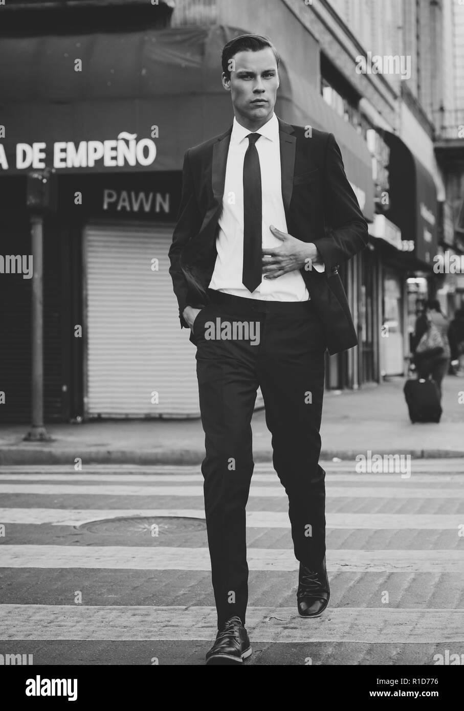 Ein Schwarz-Weiß-Porträt einer männlichen Modell zu Fuß auf den Straßen der Innenstadt von Los Angeles. Er ist gut aussehend und gut in einem schwarzen Anzug und Krawatte. Stockfoto