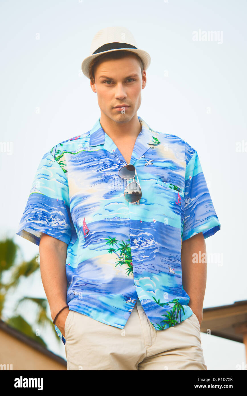 Ein schönes männliches Modell im Sommer Shirt outdoor vor blauem Himmel posieren. Er trägt einen weißen Fedora Hut. Stockfoto
