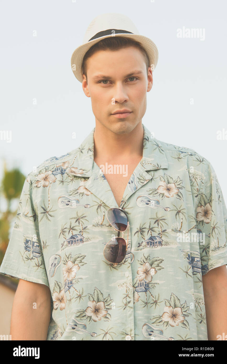 Ein schönes männliches Modell im Sommer Shirt outdoor vor blauem Himmel posieren. Er trägt einen weißen Fedora Hut. Stockfoto