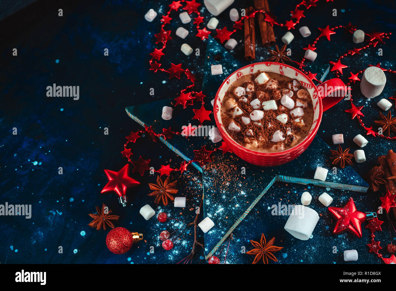 Heißer Kakao winter Flach. Rot Tasse Weihnachten Schokolade auf einem sternförmigen Coaster mit mini Marshmallow, Zimt, und Dekorationen. Der dunkle Hintergrund w Stockfoto