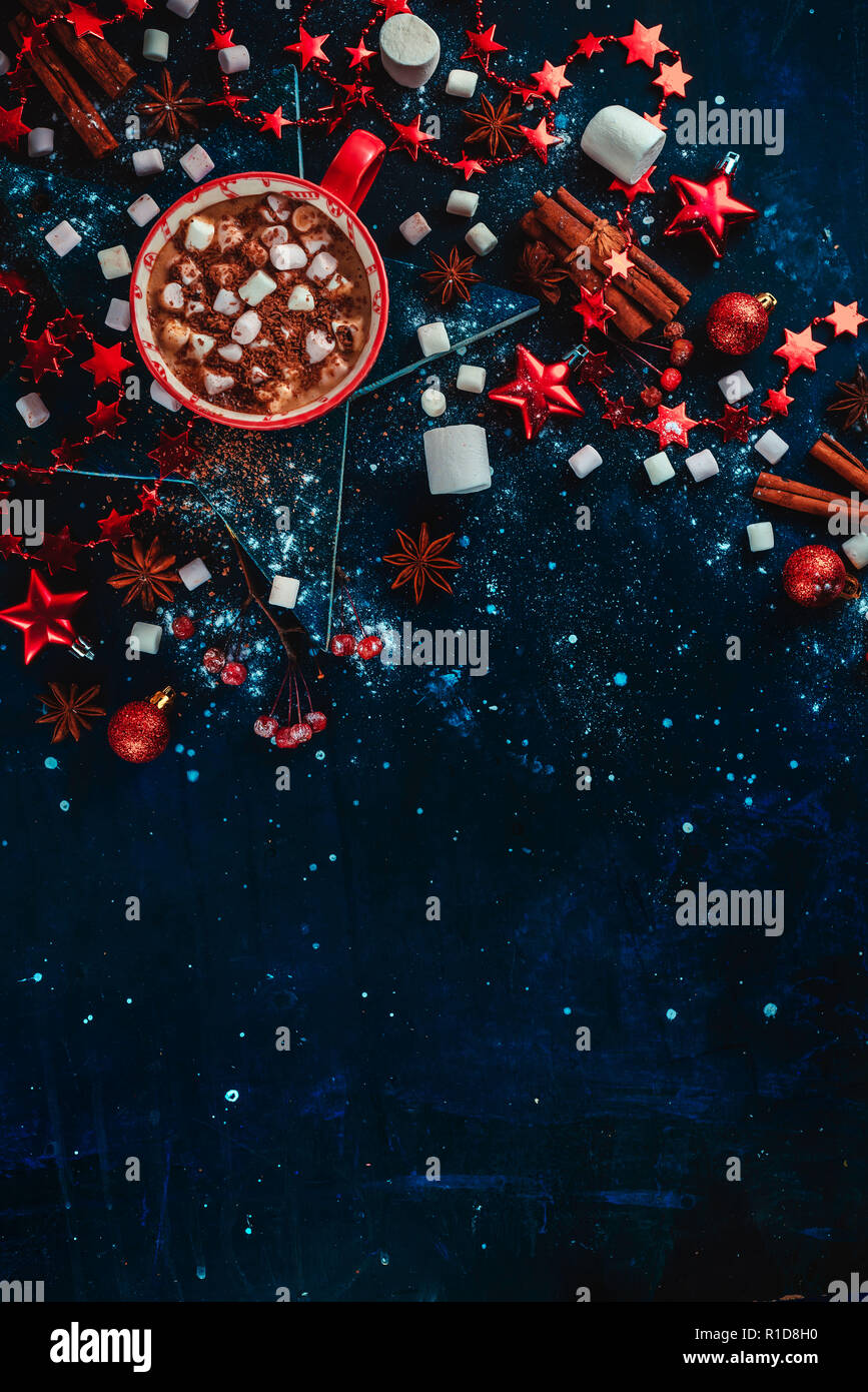 Heißer Kakao winter Flach. Rot Tasse Weihnachten Schokolade auf einem sternförmigen Coaster mit mini Marshmallow, Zimt, und Dekorationen. Der dunkle Hintergrund w Stockfoto