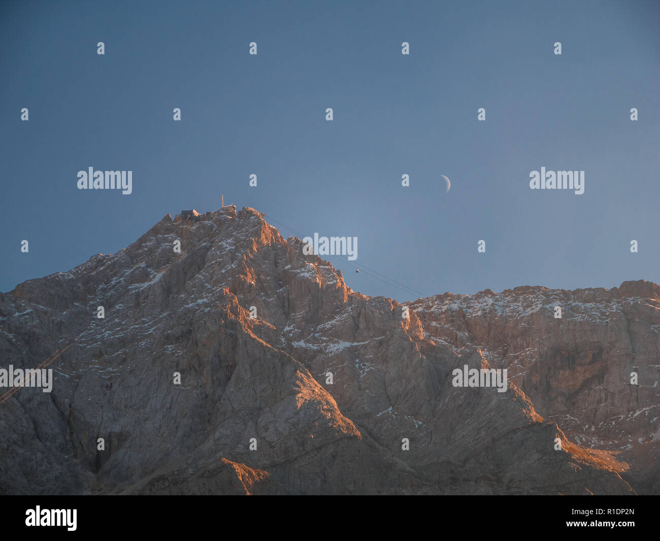Schließen Sie herauf Bild vom höchsten Berg die Zugspitze Deutschland mit Mond und Gondel bei Sonnenuntergang Stockfoto